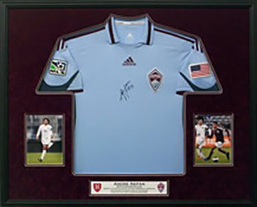 Framed blue soccer jersey with photographs.
