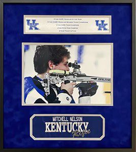 Framed shooting award with athlete and rifle.