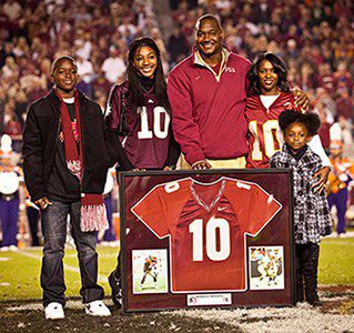 Family posing with framed football jersey.