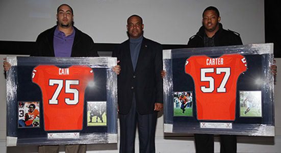 Three men holding framed football jerseys.