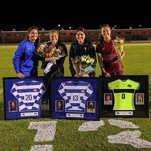 Soccer players holding flowers and framed jerseys.