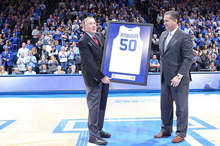 Two men holding framed sports jersey.