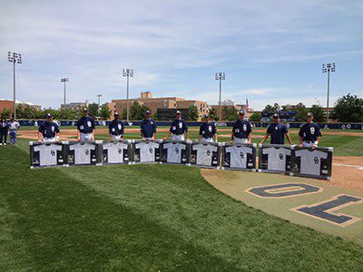 Baseball players holding framed jerseys on field