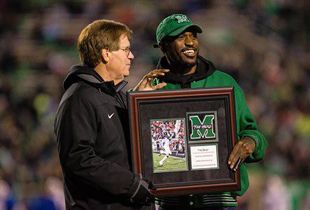 Two men holding a framed sports photo.